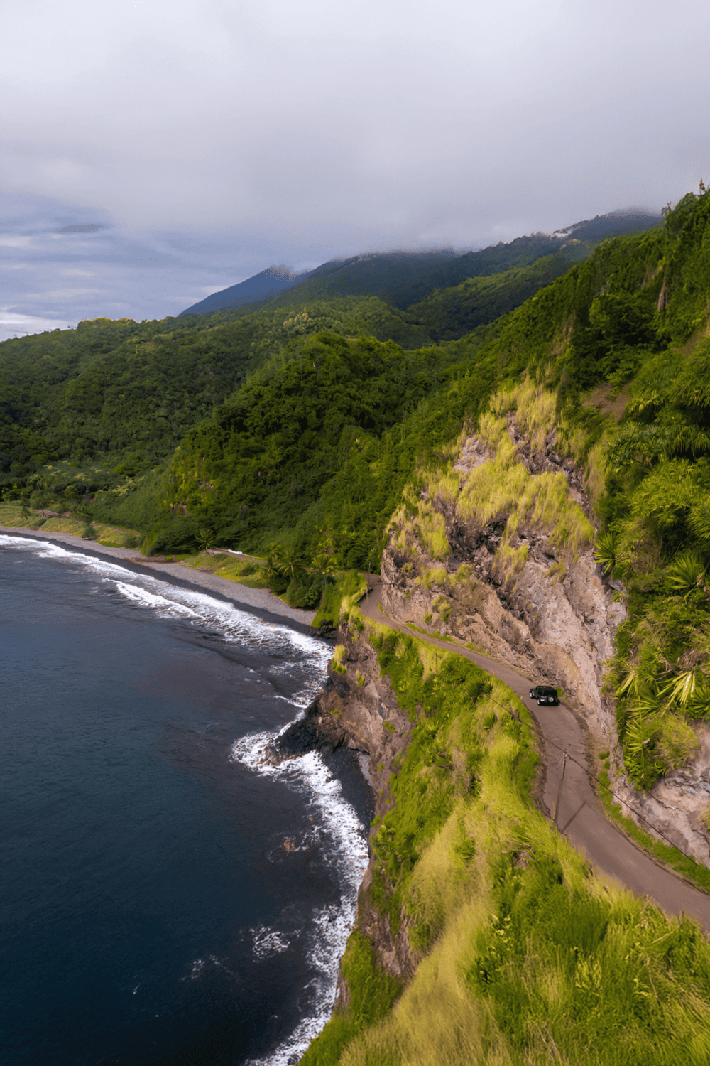 Breathtaking coastal road along lush green mountains and ocean, ideal for scenic driving and adventure.