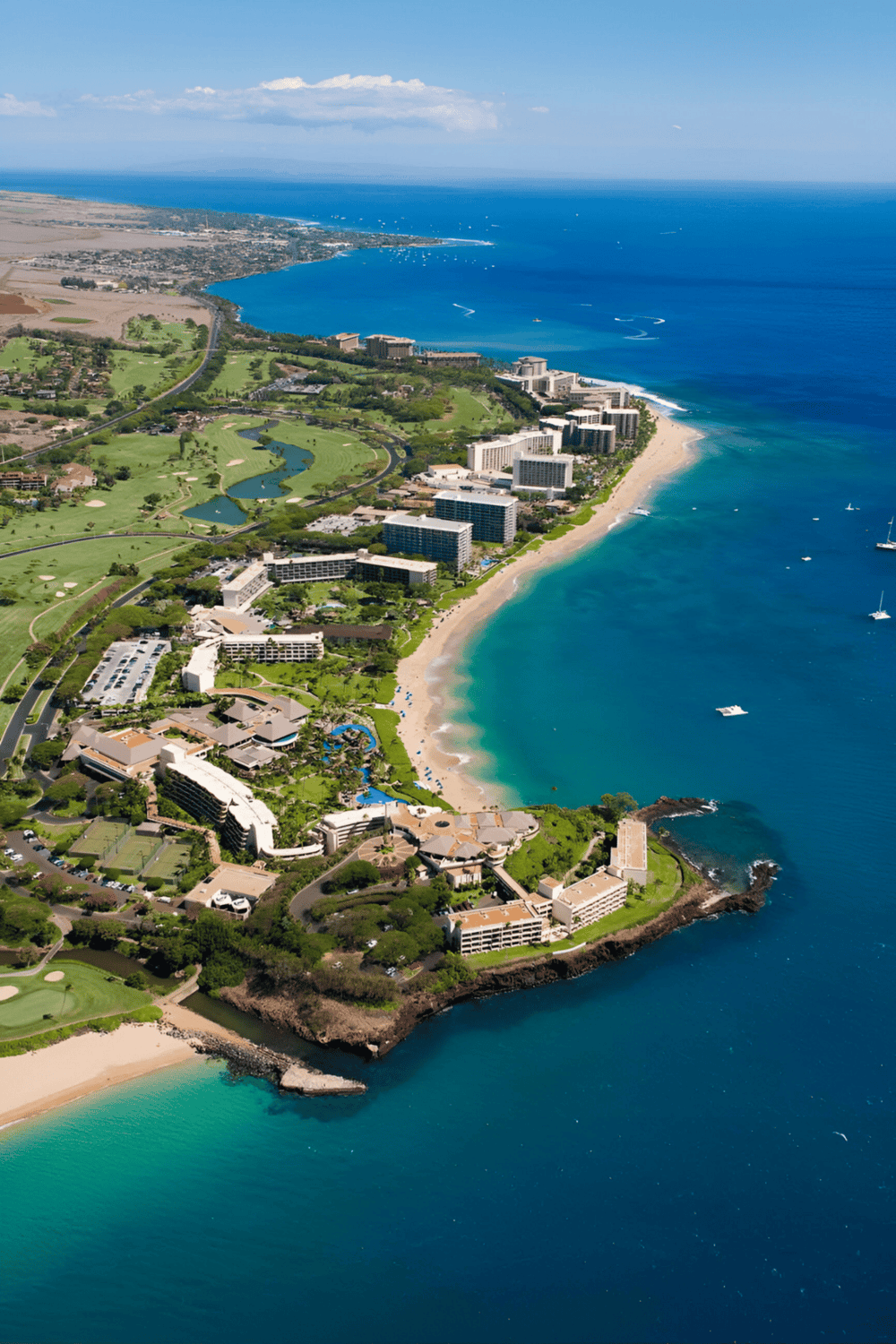 Breathtaking aerial view of the oceanfront resort, sandy beach, and lush golf course along the coastline.