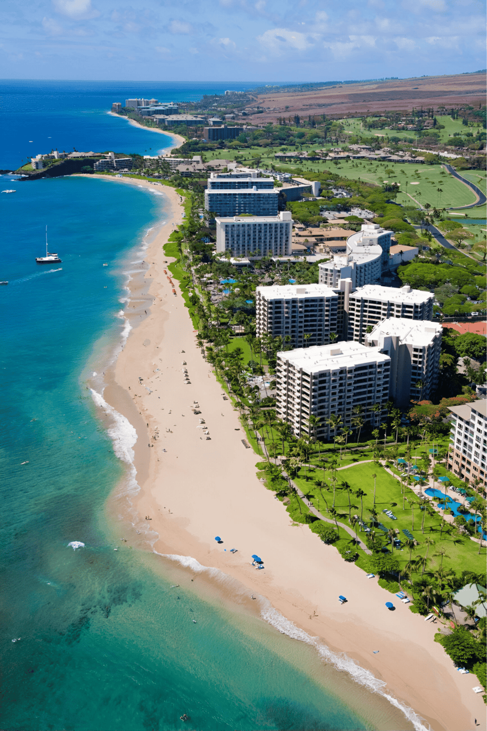 Seaside resort with beachfront hotels and lush green golf courses, Hawaii coast, scenic ocean views, luxurious vacation destination.
