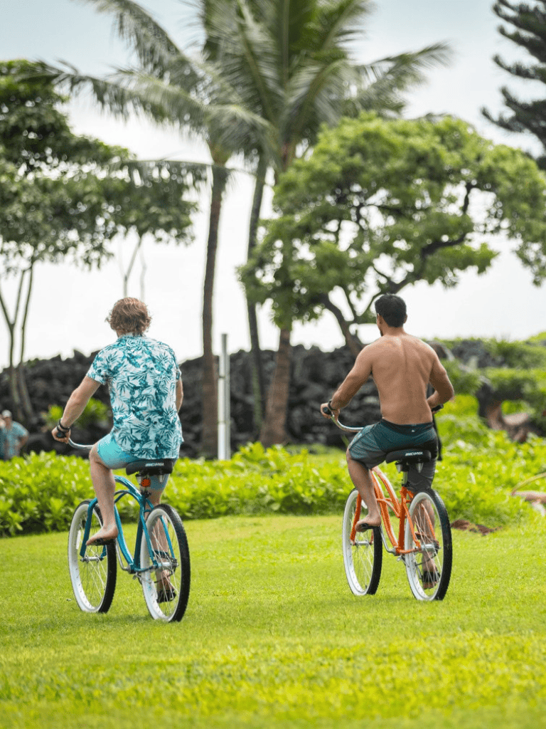Bright tropical park with two people riding bicycles under palm trees for outdoor recreation and fitness.