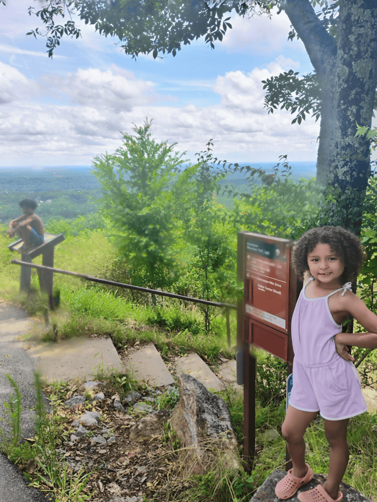 Scenic mountain overlook with children enjoying nature and view, quest for directions outdoor adventure.