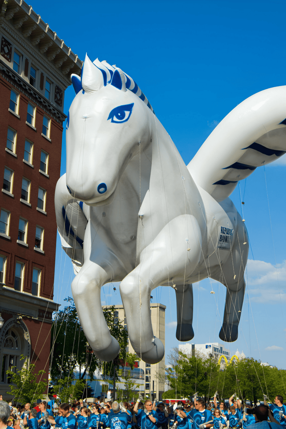 1. Large inflatable white horse balloon in city street during parade.