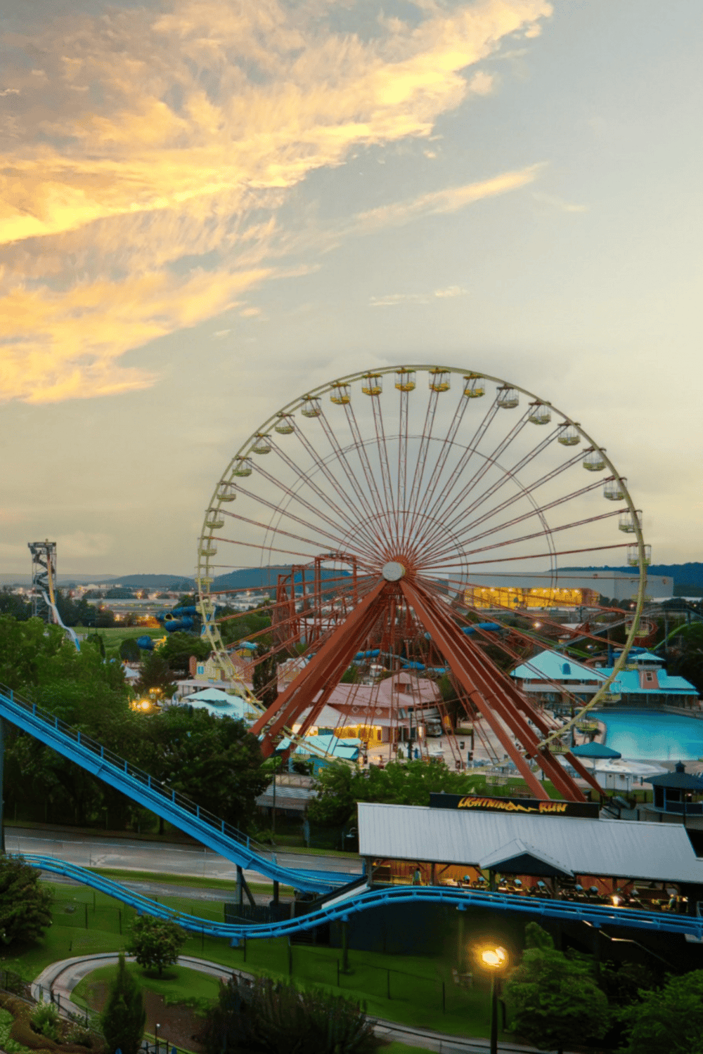 Amusement park with Ferris wheel and roller coasters at sunset, family-friendly entertainment and fun attractions.