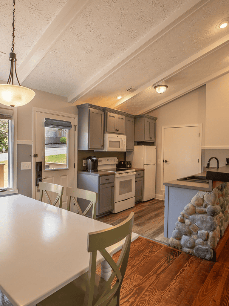 Bright modern kitchen with gray cabinets, white appliances, and cozy stone accents.
