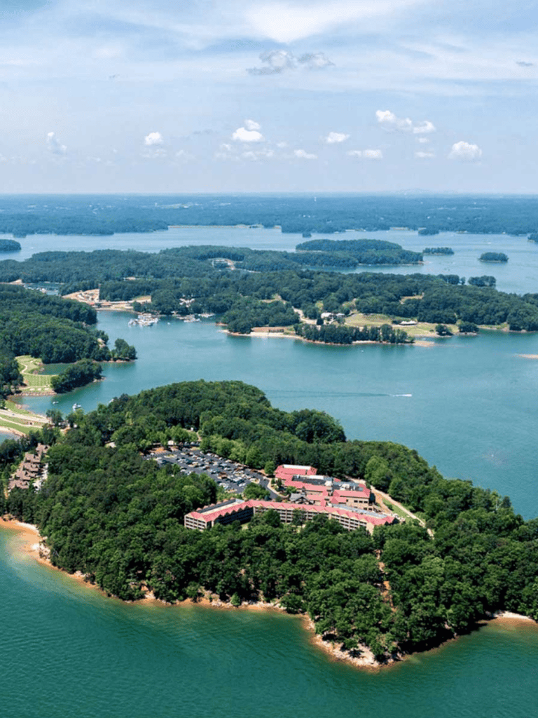 Aerial view of a lakeside resort with lush greenery and multiple islands in the background.