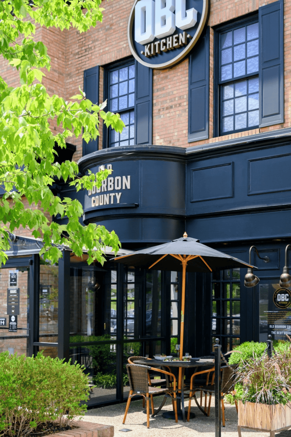 1. Exterior view of OBC Kitchen in Bourbon County with outdoor seating and lush greenery.