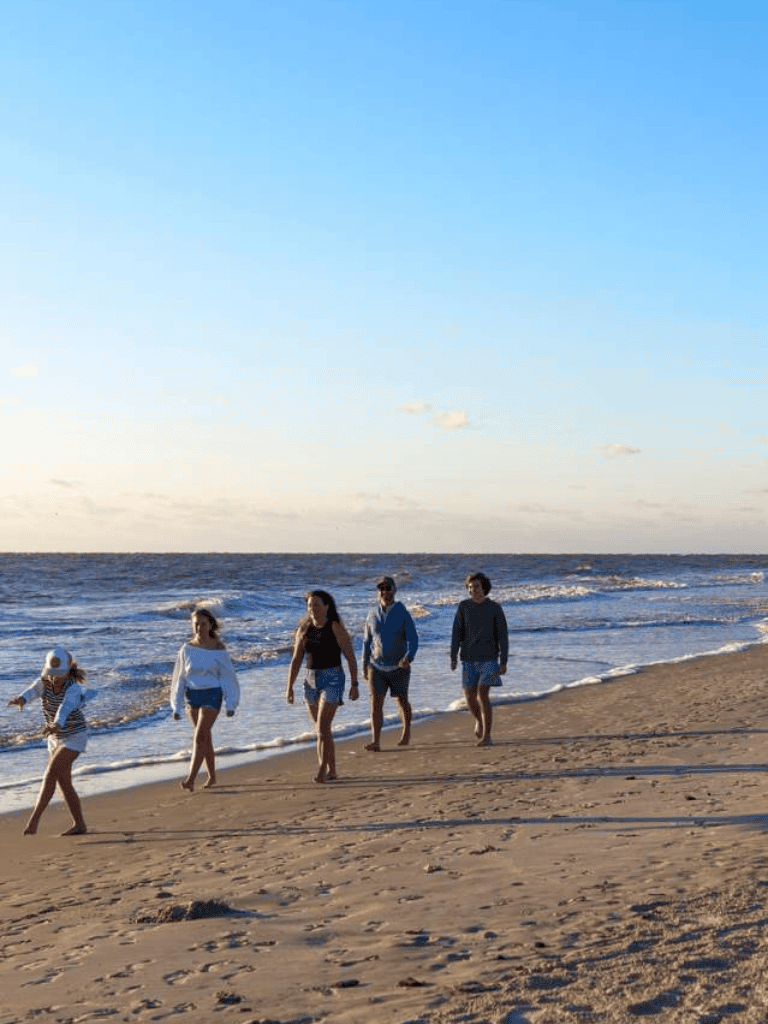 Relaxed beach walk with family on sandy shoreline during sunny day at the ocean.