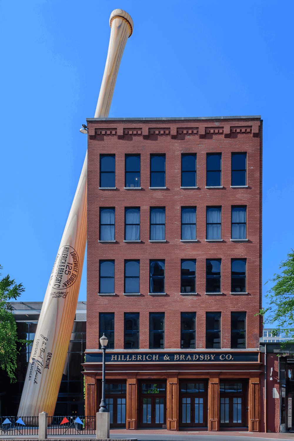 Pencil sculpture towering beside historic red brick building in downtown Louisville.