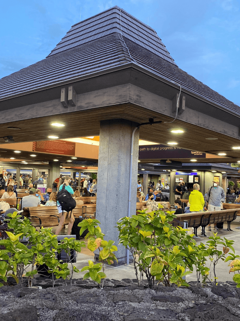 People waiting at the airport terminal, with seating and modern architecture.