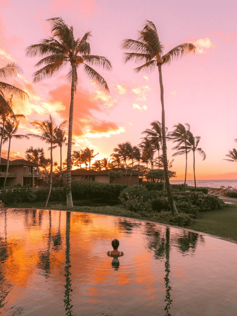 Relaxing tropical sunset poolside with palm trees and ocean view, perfect for vacationers seeking serene coastal escapes.