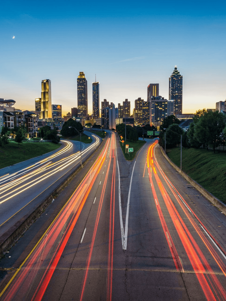 Bright city skyline with highway light trails at dusk, Atlanta urban driving directions, traffic routes, cityscape.