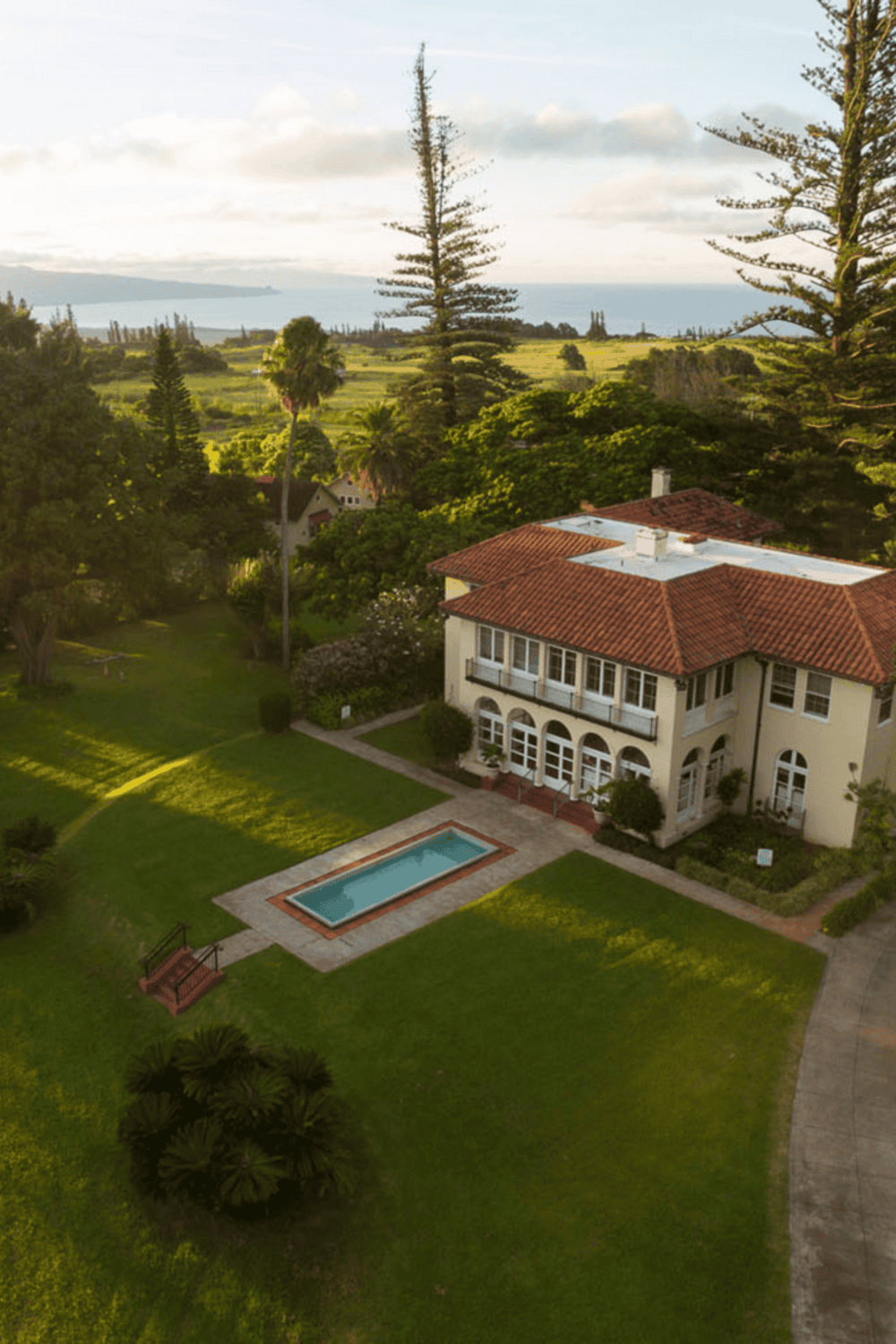 Elegant coastal mansion with swimming pool and lush gardens, offering scenic ocean views.