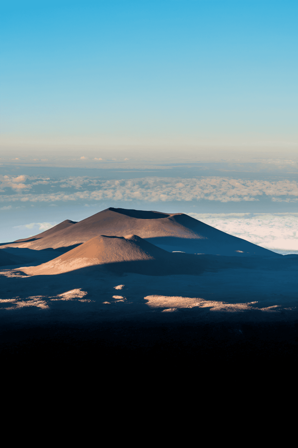 Aerial view of volcanic mountains above clouds during daytime, scenic landscape, natural wonders, travel inspiration.