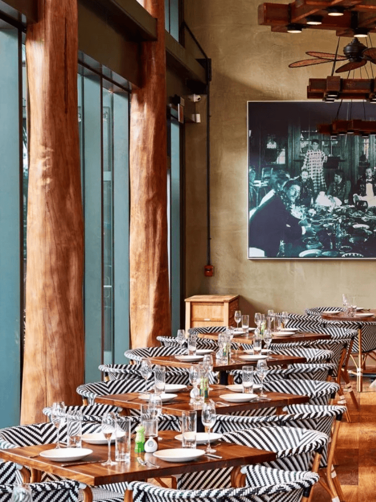 Modern restaurant interior with wood accents and black and white striped chairs for dining experience.