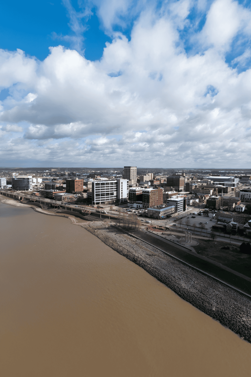 Modern city skyline near river with buildings and partly cloudy sky for urban navigation.
