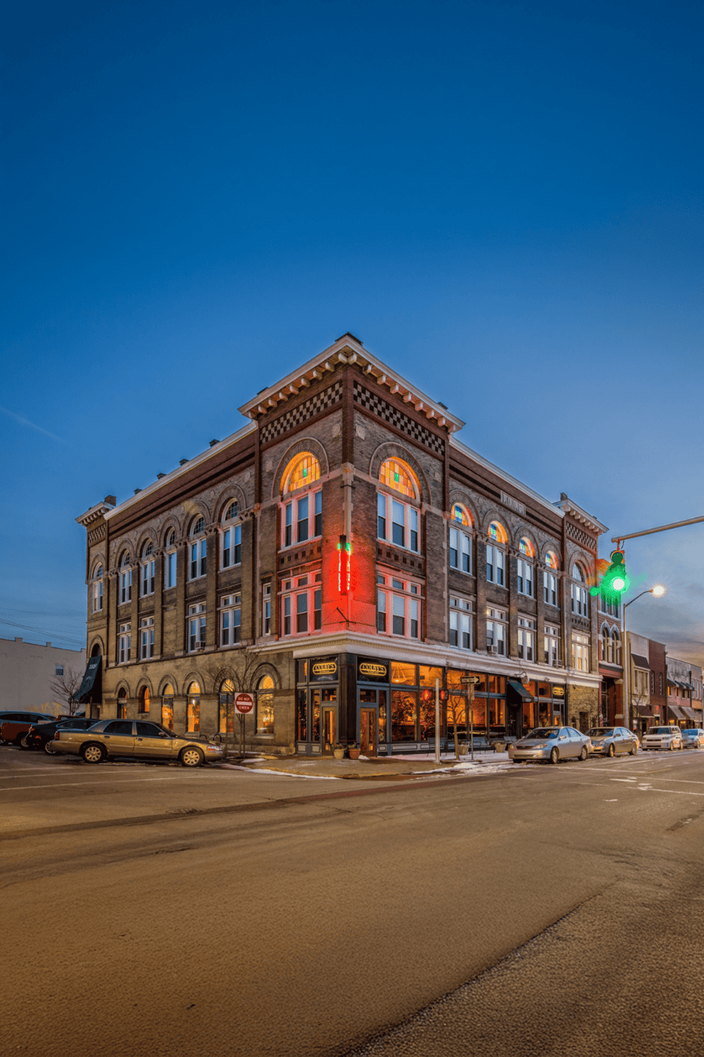 Historic downtown building with colorful stained glass windows at dusk, illuminated for a vibrant city nightlife scene.