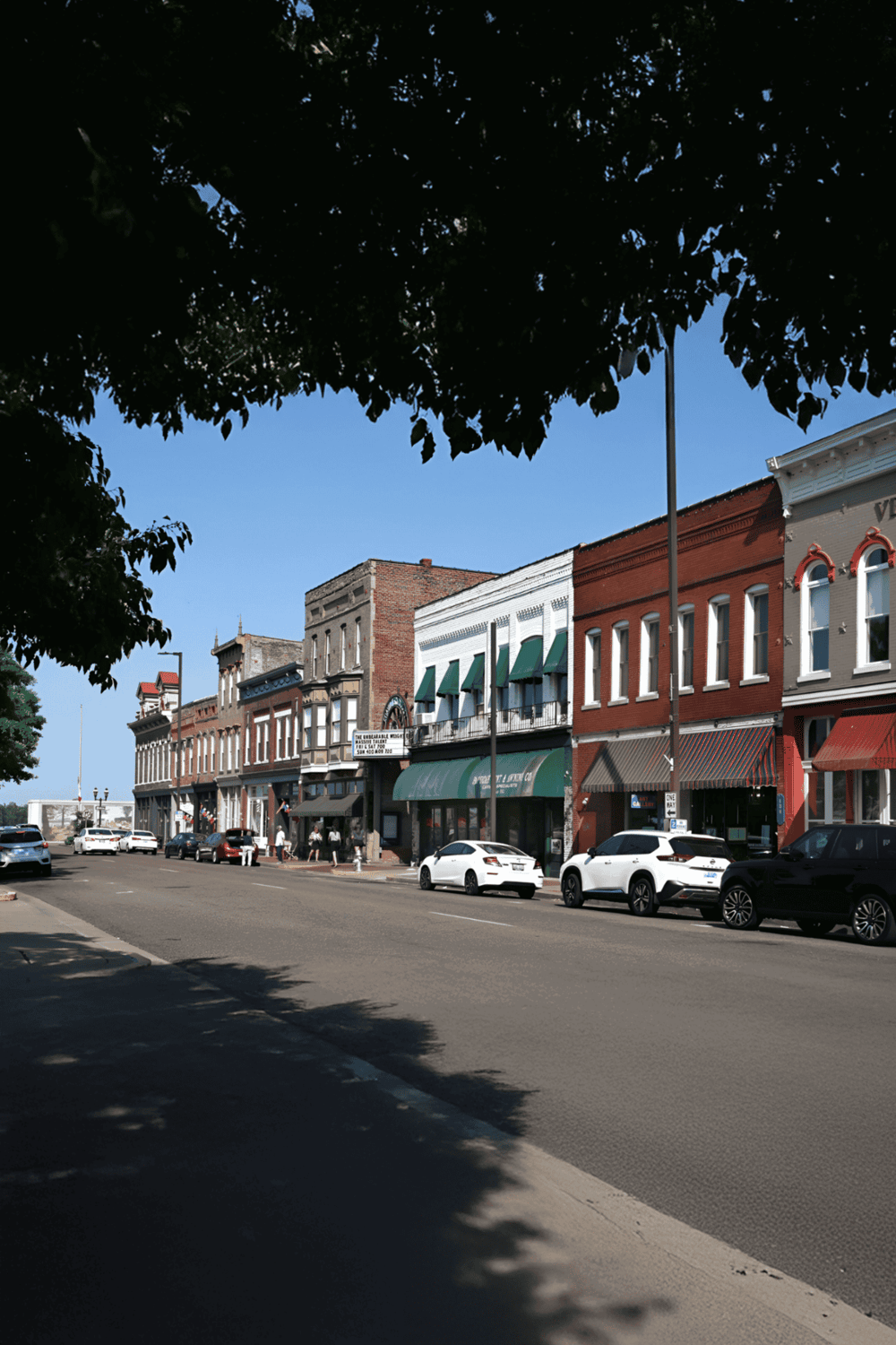 Colorful historic downtown street with shops and parked cars, perfect for exploring local attractions and directions.