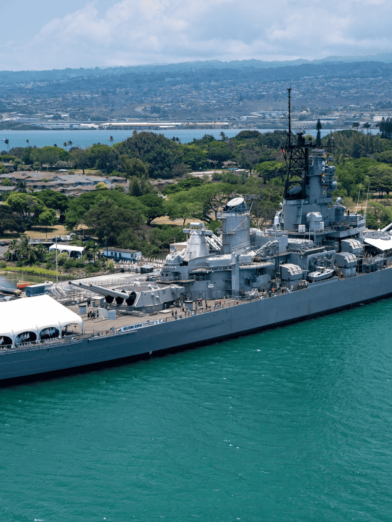 U.S. Navy battleship docked in San Diego harbor with cityscape and mountains background.