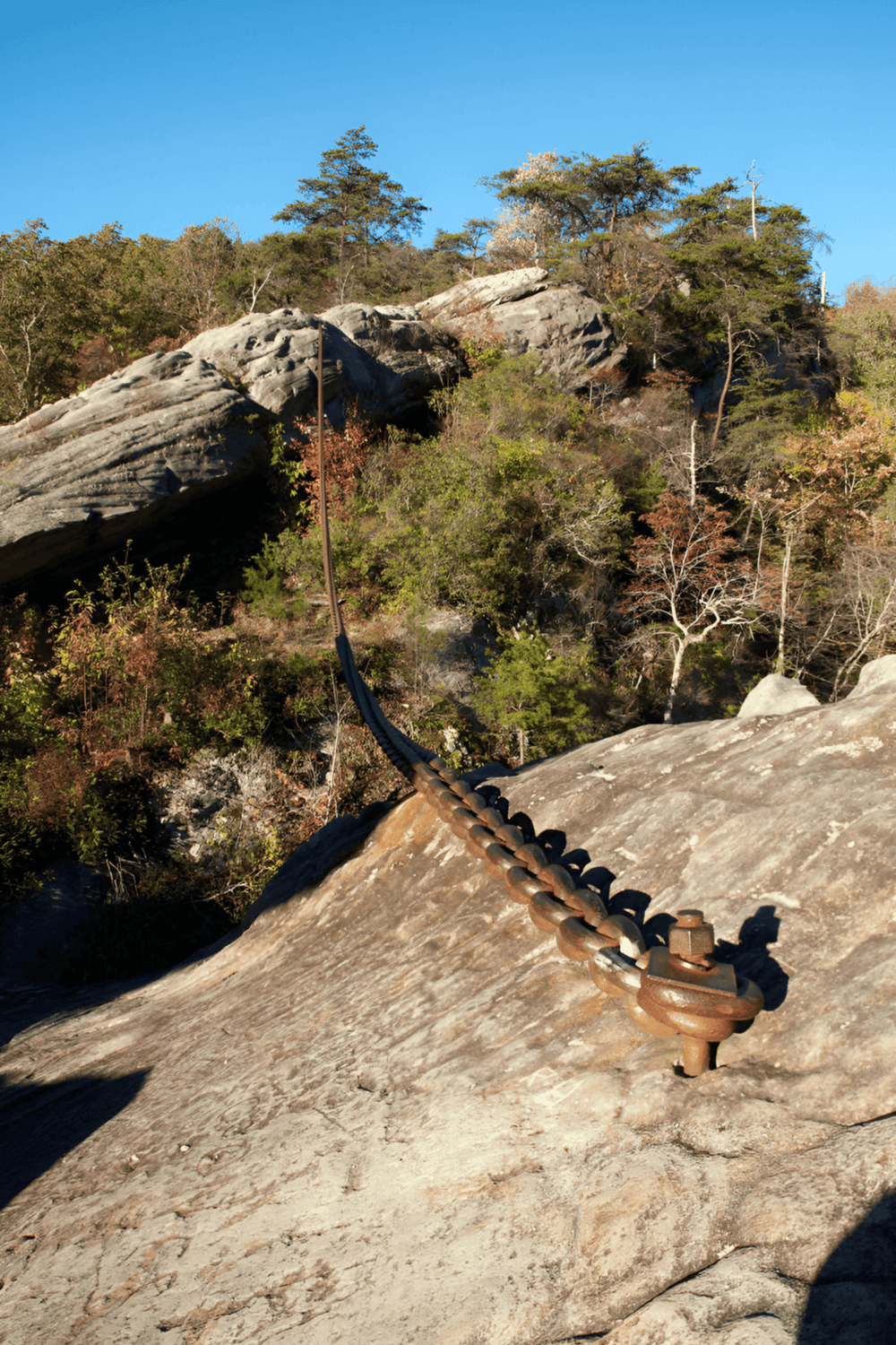 Climbing rugged rock terrain on a mountain with secured chains for safety and navigation.