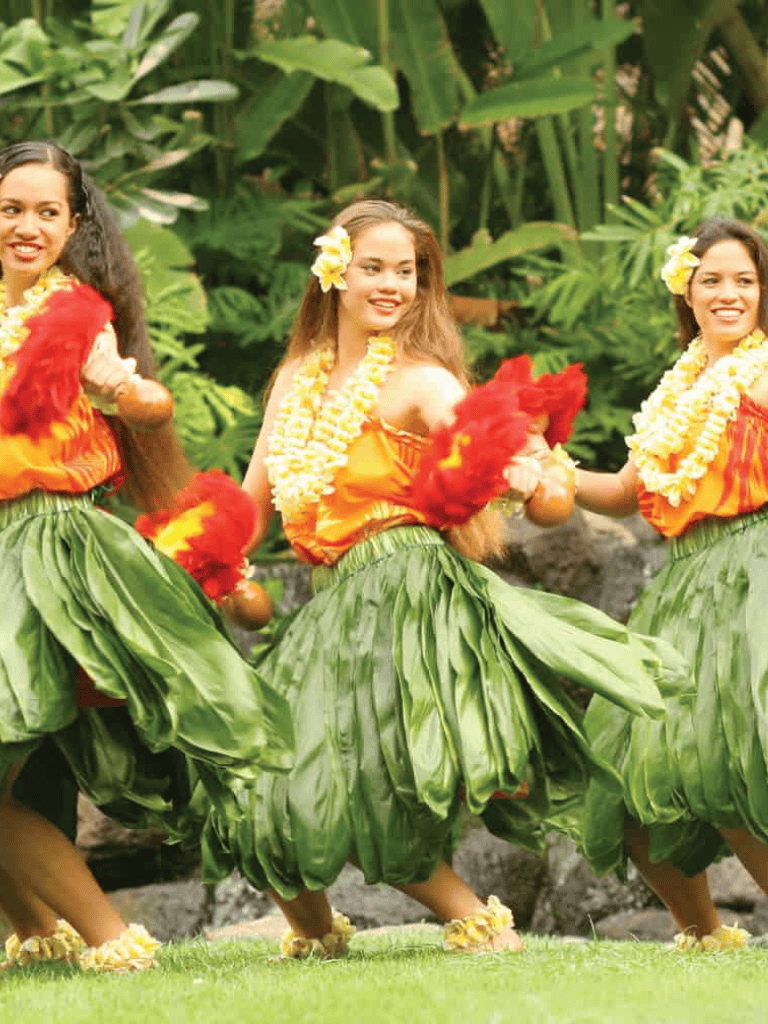 Colorful traditional Hawaiian hula dancers performing in lush tropical garden setting.