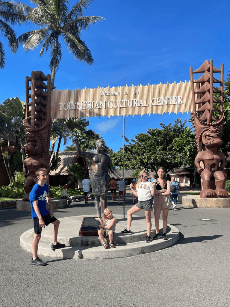 Vibrant Polynesian Cultural Center entrance with traditional carvings and welcoming atmosphere.
