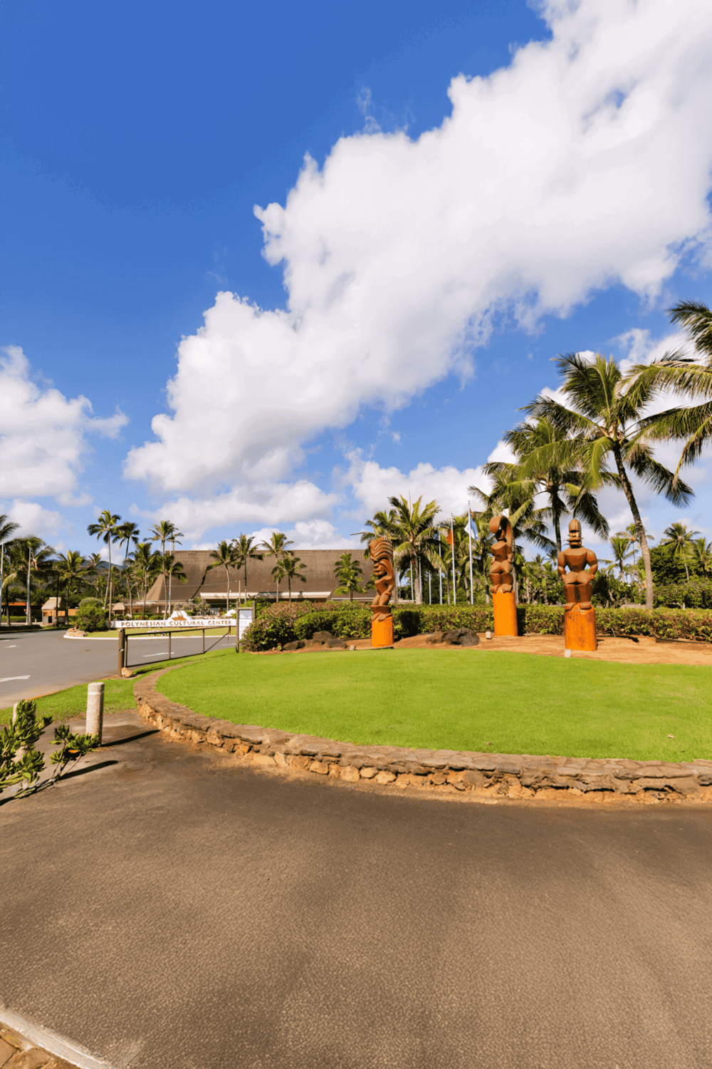 Vibrant Polynesian cultural center entrance surrounded by tropical palm trees and traditional tiki statues.