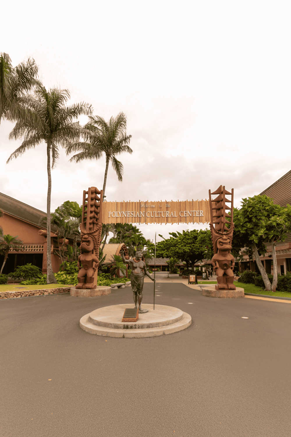 Polynesian Cultural Center entrance with traditional tiki statues and lush tropical landscaping.