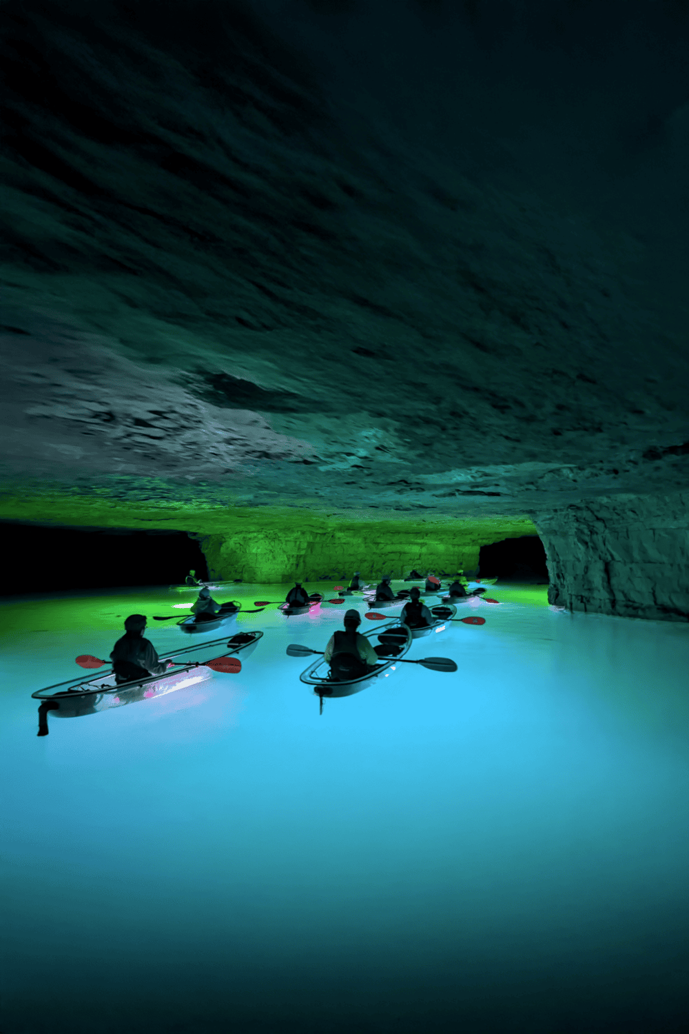 Vivid underground cave kayaking adventure illuminated by colorful LED lights.