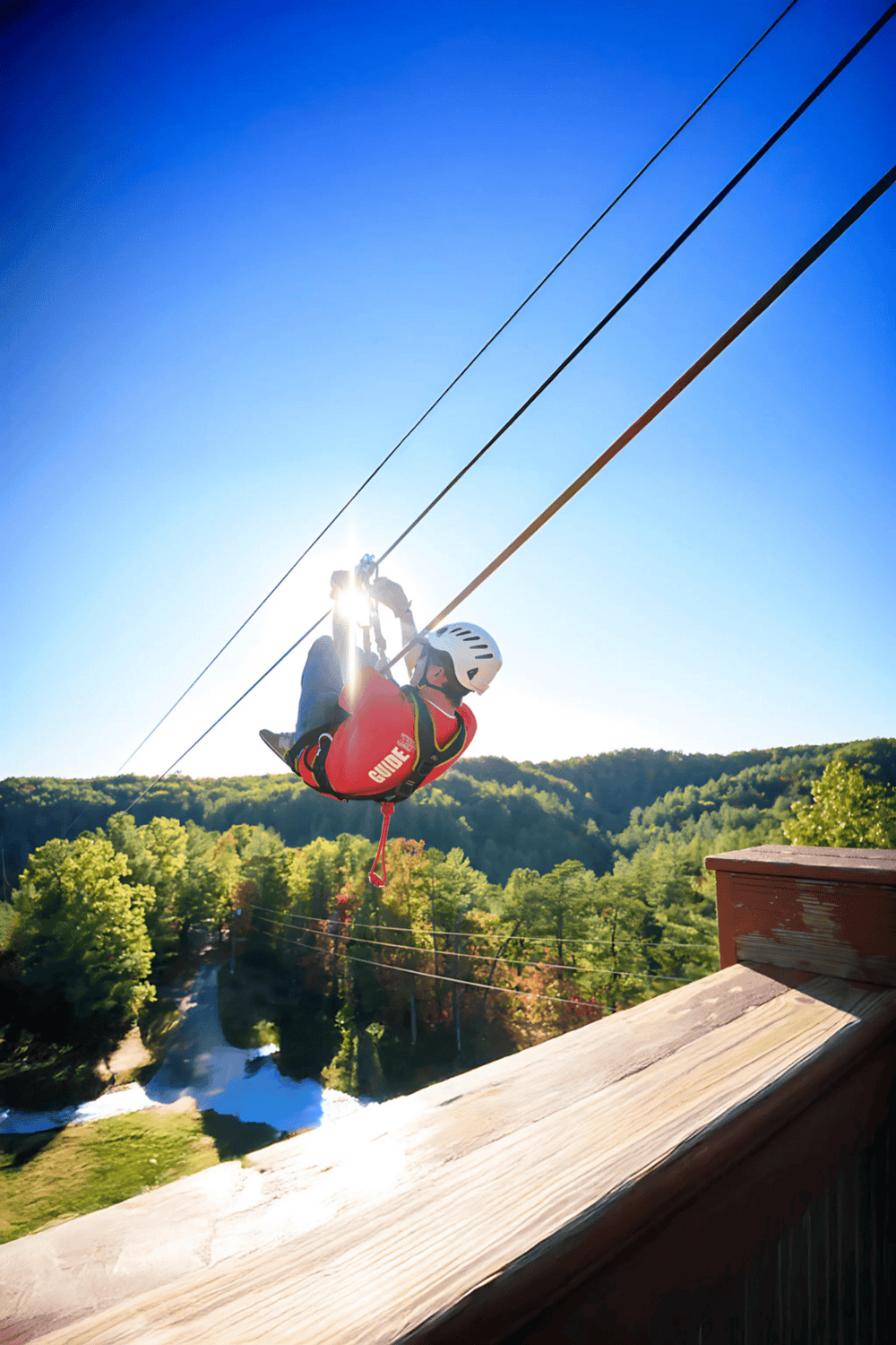 1. Thrilling zipline ride through lush green forest with blue sky backdrop.