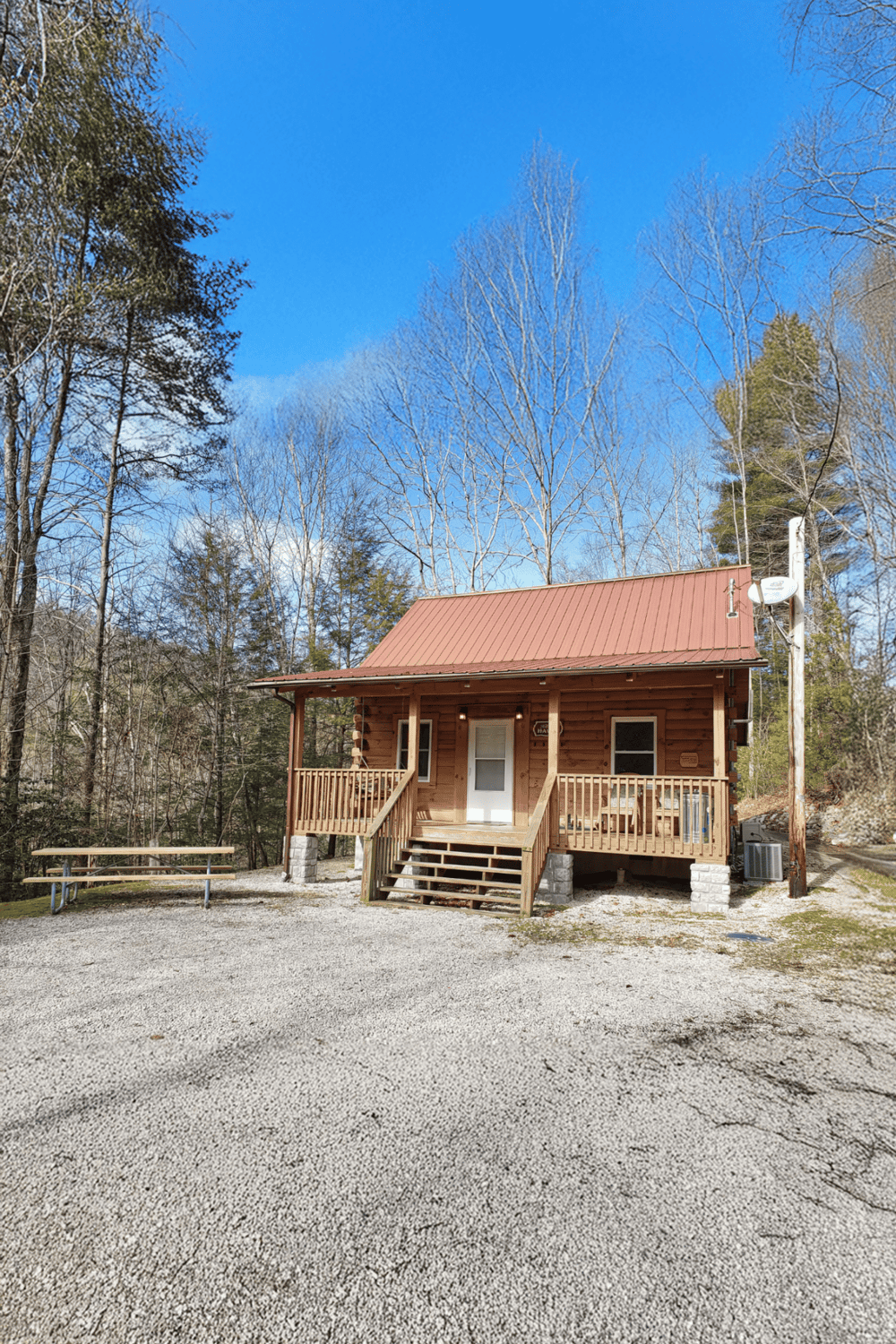 Cozy cabin with wood porch, surrounded by trees, perfect for outdoor getaways and nature adventures.