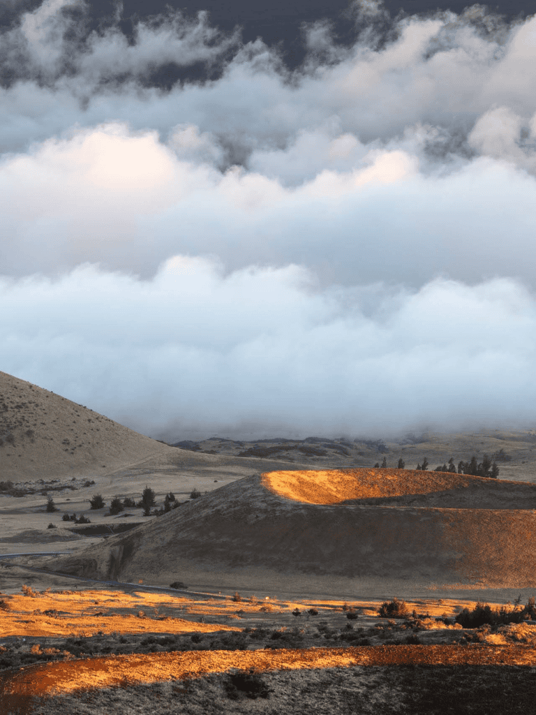 Rolling hills national park landscape with dramatic clouds and warm sunset lighting.