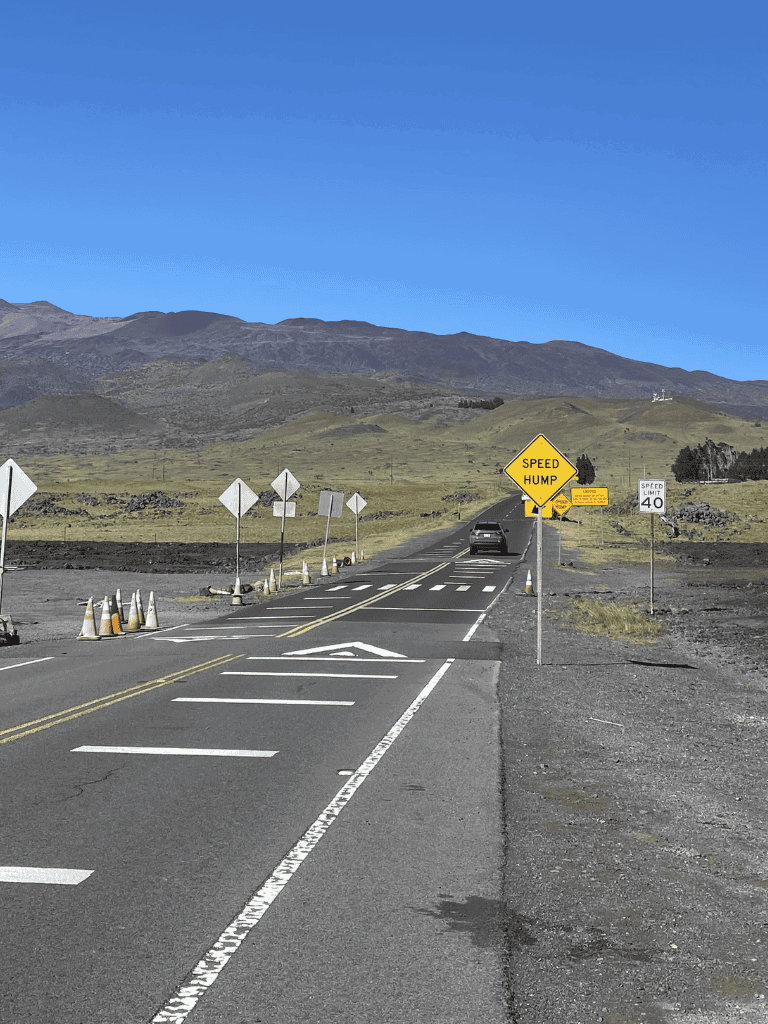 Speed hump road sign warning for drivers on scenic rural highway with mountainous background.