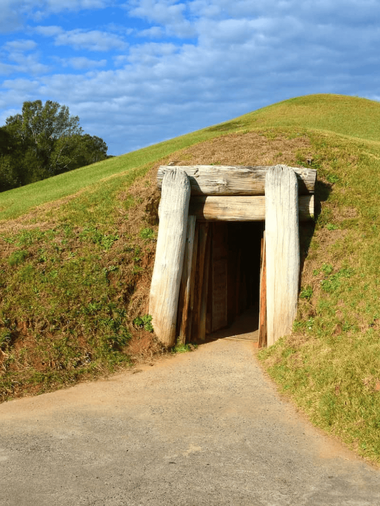 Ancient burial mound with wooden entrance, part of historic American archaeological site.