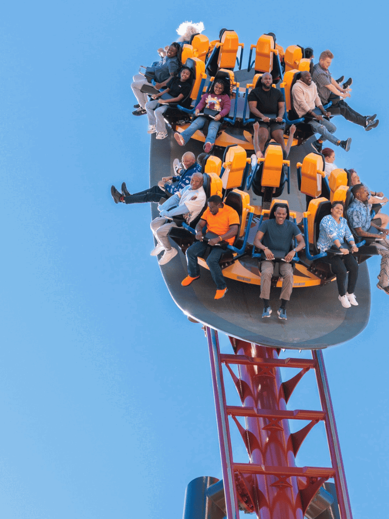 Thrilling amusement park ride with diverse group of riders enjoying the high-speed roller coaster.