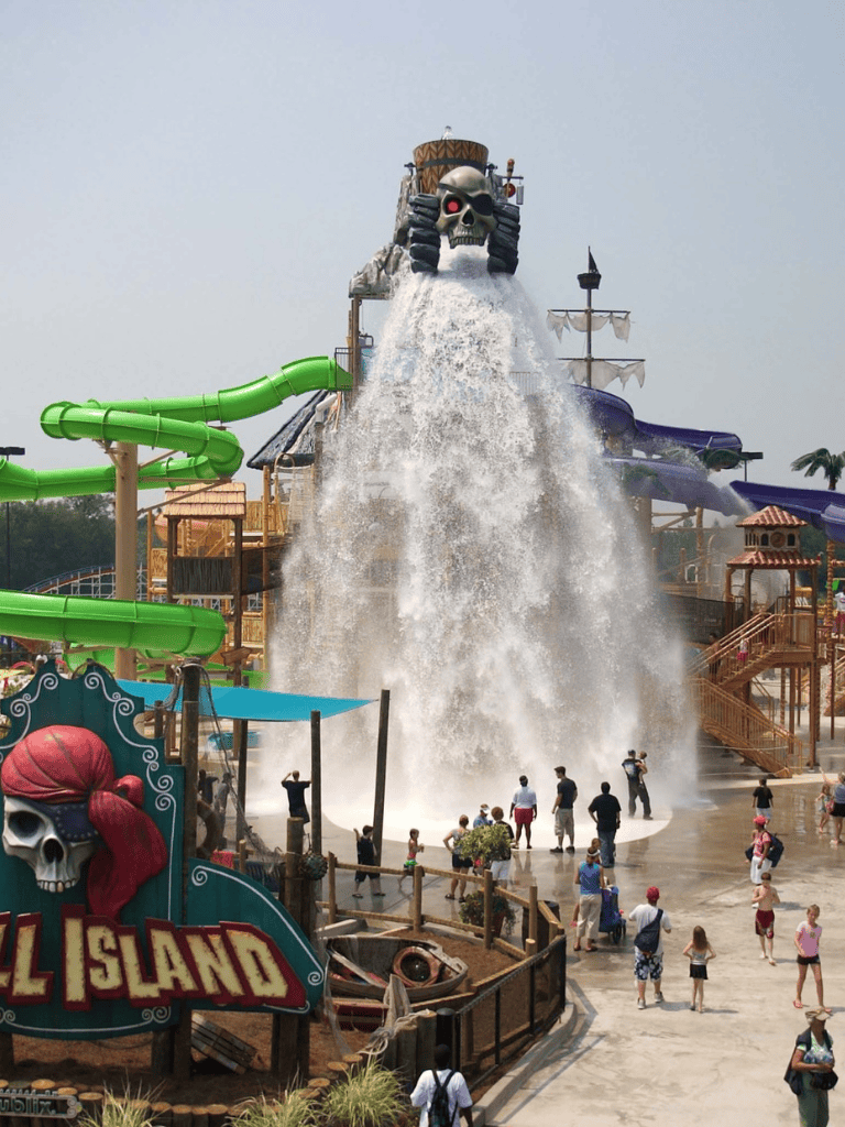 Water park pirate themed water slide with skull and water splash.