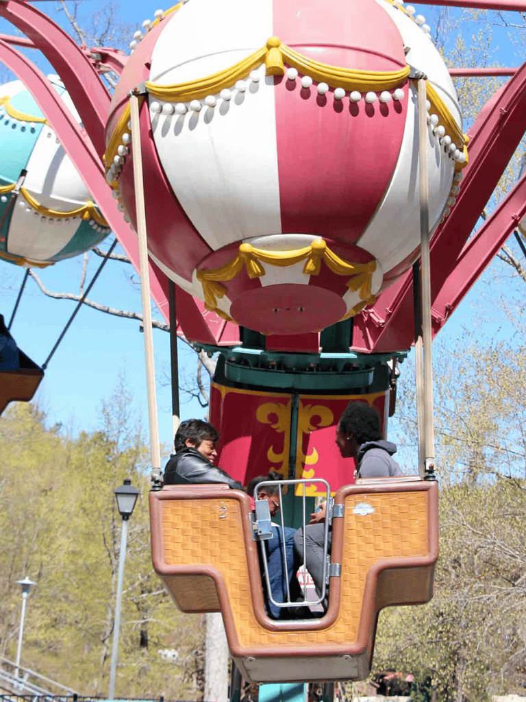 Swing ride at amusement park with colorful hot air balloon design, children enjoying funfair experience.