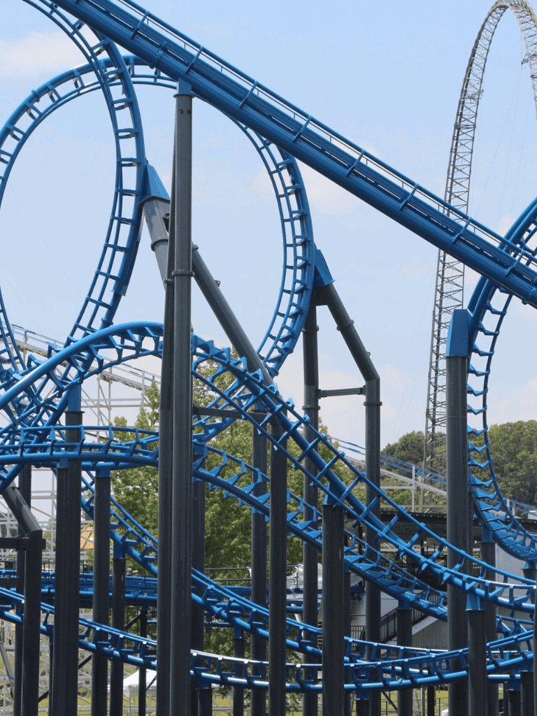 Blue roller coaster track at amusement park with loops and twists.