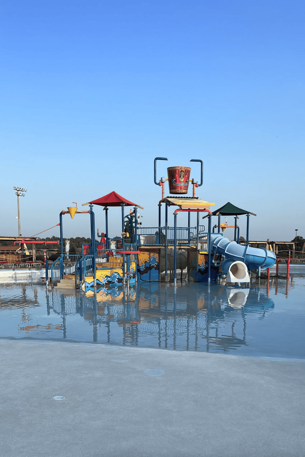 Colorful water park play structure with slides and water features on a sunny summer day.