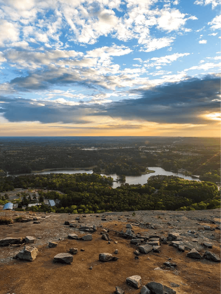 Breathtaking view of the sunset over a river and lush greenery from a mountain peak.