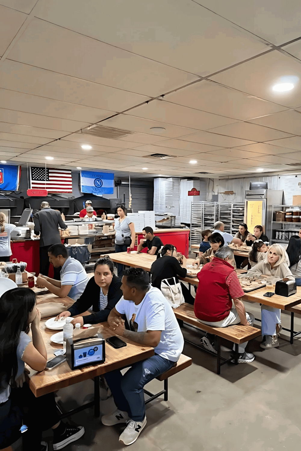 American flag and sports flags at a restaurant, people dining, casual atmosphere.
