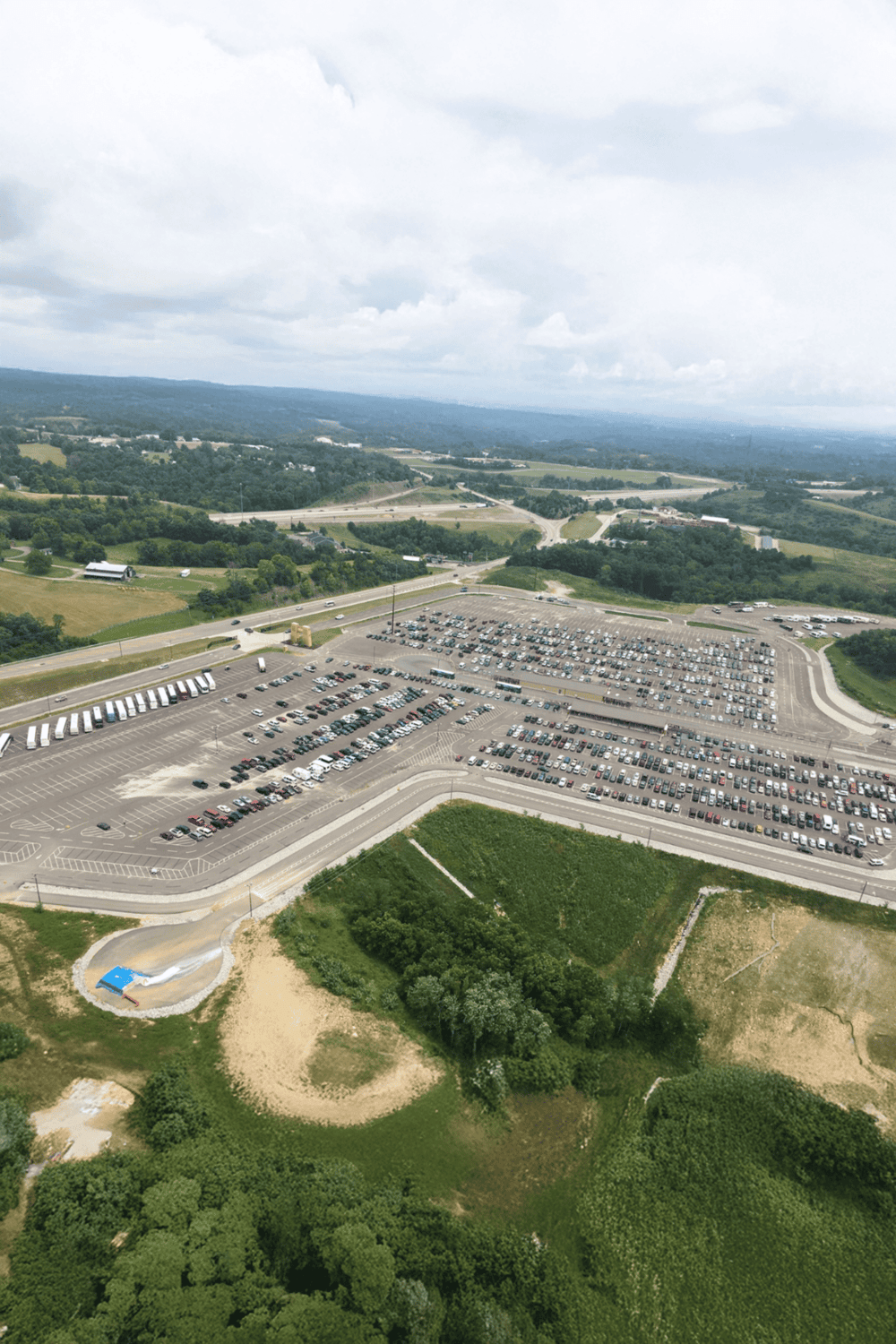 Empty parking lot with surrounding greenery and highway access, ideal for directions and navigation services.