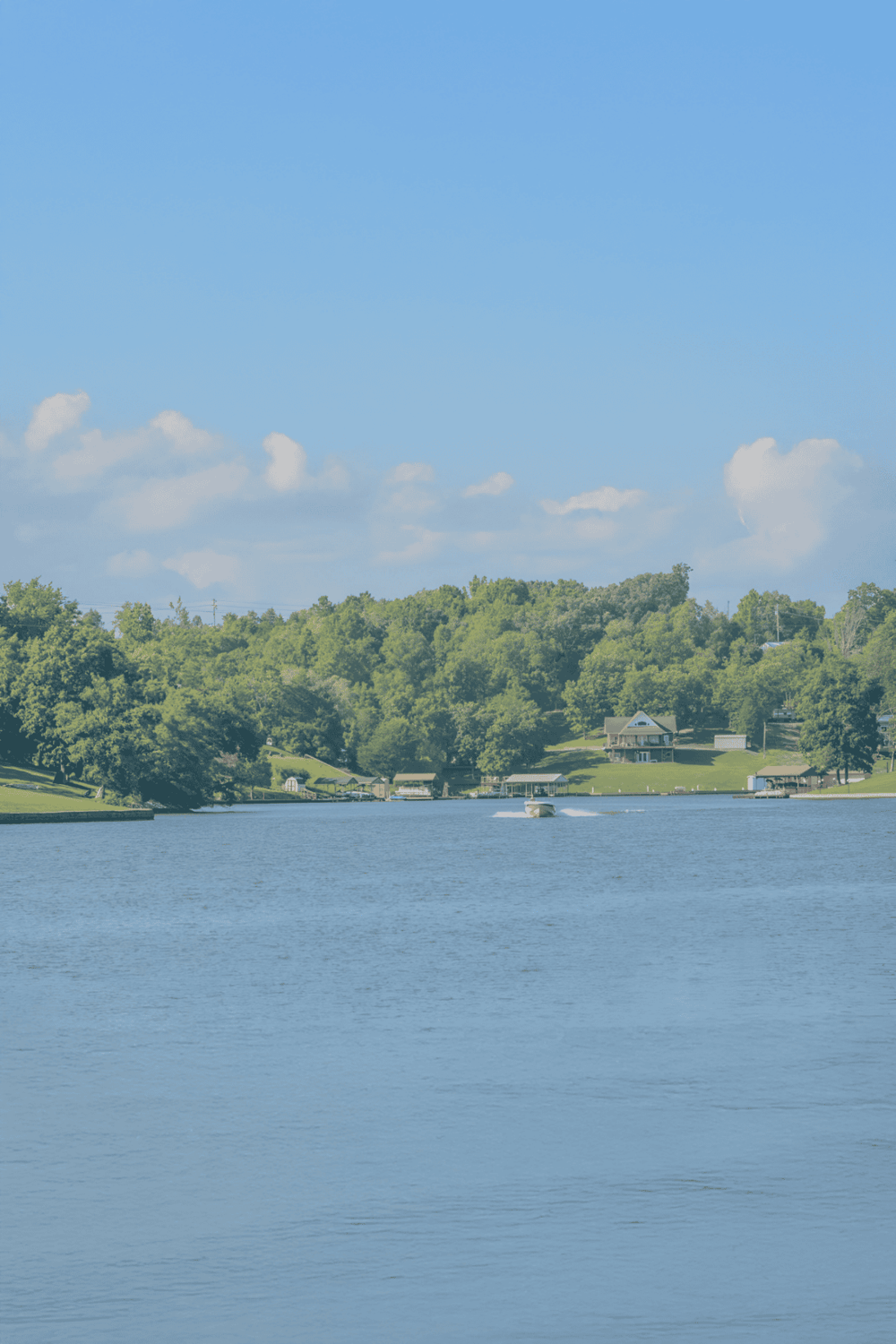 Serene lake with lush green surroundings and clear blue sky, perfect for outdoor exploration and navigation.