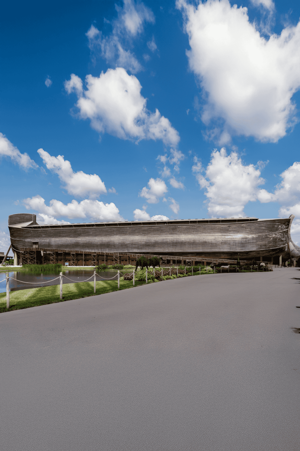 Old wooden ship monument reflecting history and maritime adventure, set against a bright blue sky with fluffy white clouds.