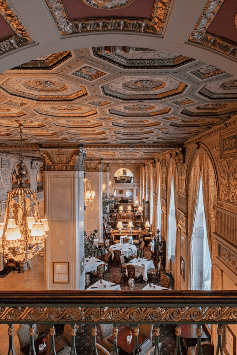 Ornate hotel dining room with elaborate ceiling, elegant chandeliers, and luxurious decor.
