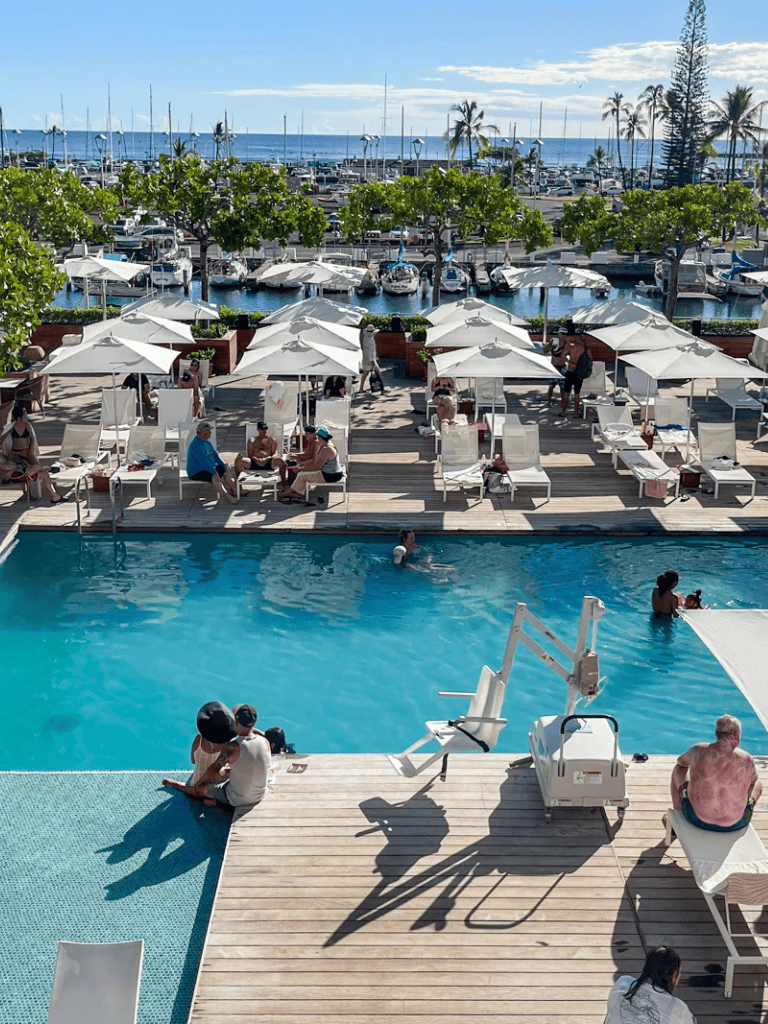 Relaxing poolside at luxury marina resort with ocean view, sun loungers, and shaded umbrellas.