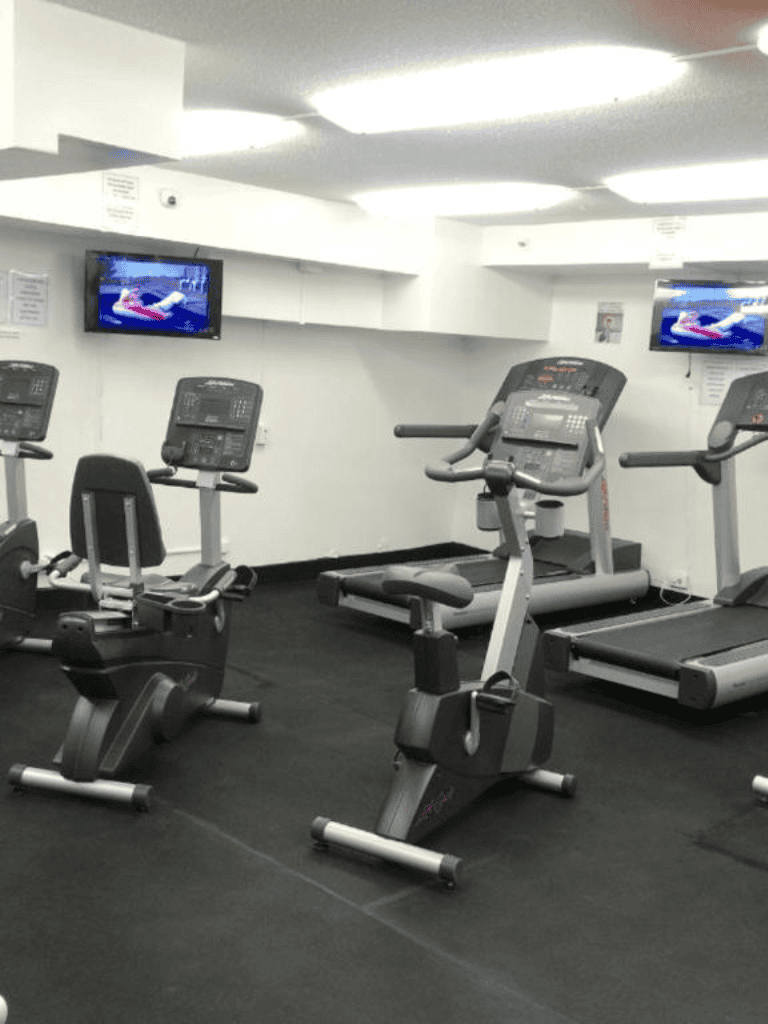 Modern gym equipment with treadmills, stationary bikes, and monitors for cardio workouts.