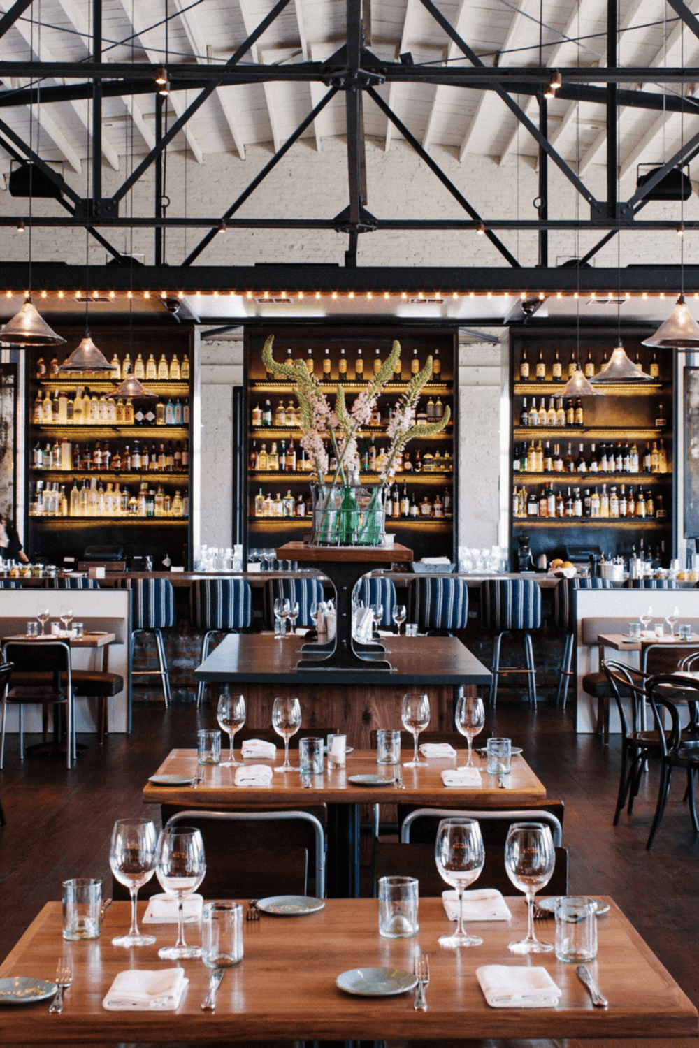 Modern restaurant interior with elegant wine display and stylish table setting for dining experiences.