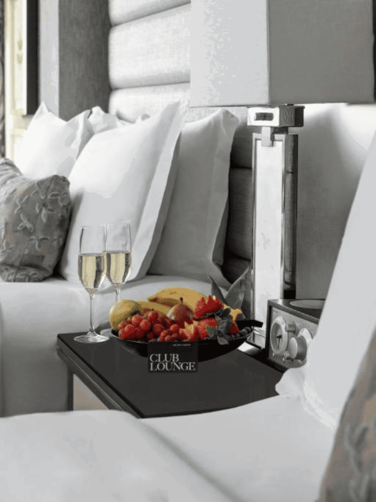 Luxurious hotel bedside with fruit platter and champagne, perfect for relaxation.
