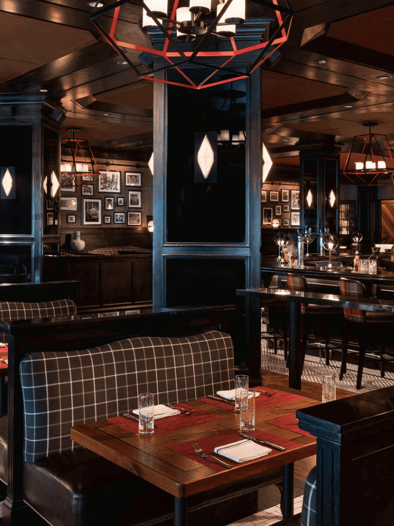 Elegant restaurant interior with cozy plaid upholstery, modern lighting, and framed artwork enhancing the ambiance.