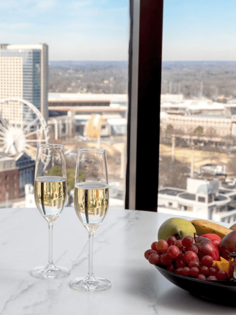 Sparkling wine glasses with city skyline view from high-rise balcony alt text.